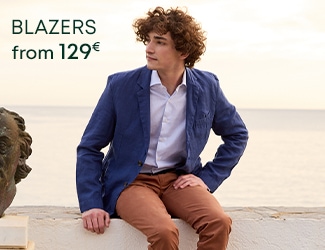 Man wearing a navy-blue blazer and a beige sweater with the text 'Blazers from 129€'